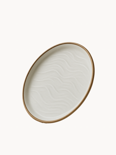Ceramiczny talerz o matowym wykończeniu w odcieniu złamanej bieli, ozdobiony strukturalnym wzorem przypominającym wydmy piaskowe i wykończony naturalnym brązowym rantem.